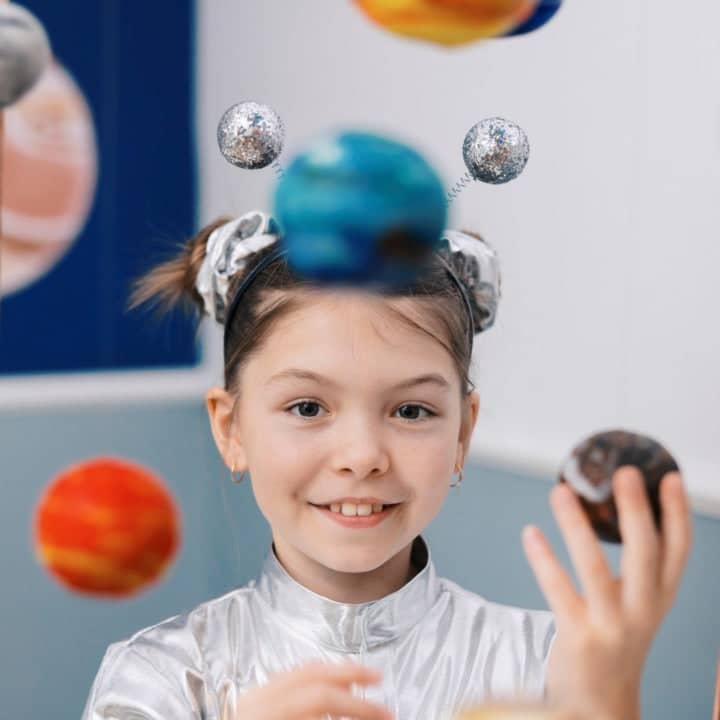 Mädchen als kleine Entdecker mit Planetenmodell spielerisch Wissenschaft und Astronomie entdecken