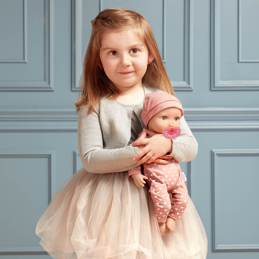 Babypuppe mit Schnuller im Pyjama mit Herzchen und Mütze