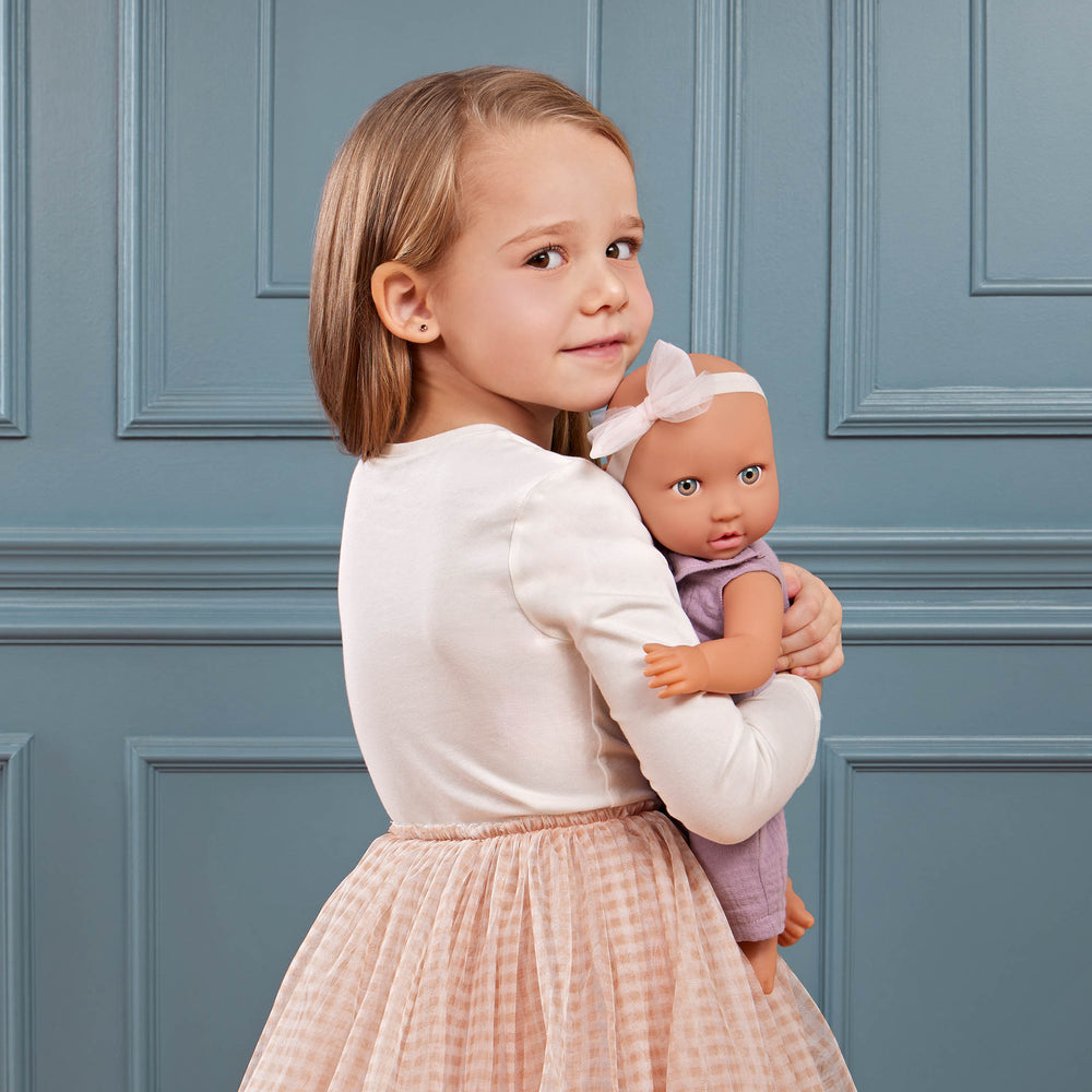 Babypuppe mit Schnuller im lila Musselinoutfit mit Stirnband