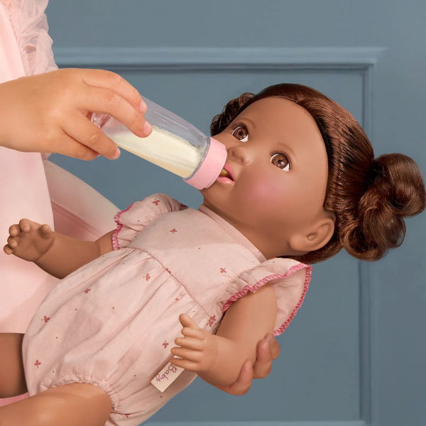 Babypuppe mit Haaren und einer Flasche mit Milcheffekt