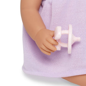 Babypuppe mit Schnuller – in einem violetten Kleid und mit einem Stirnband