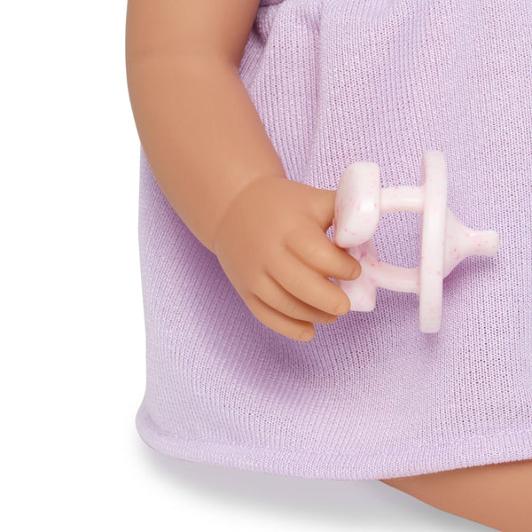 Babypuppe mit Schnuller – in einem violetten Kleid und mit einem Stirnband