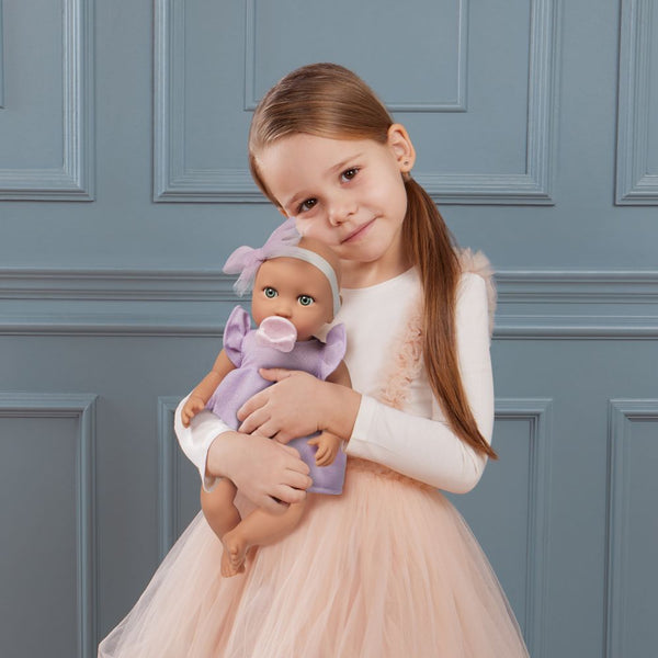 Babypuppe mit Schnuller – in einem violetten Kleid und mit einem Stirnband