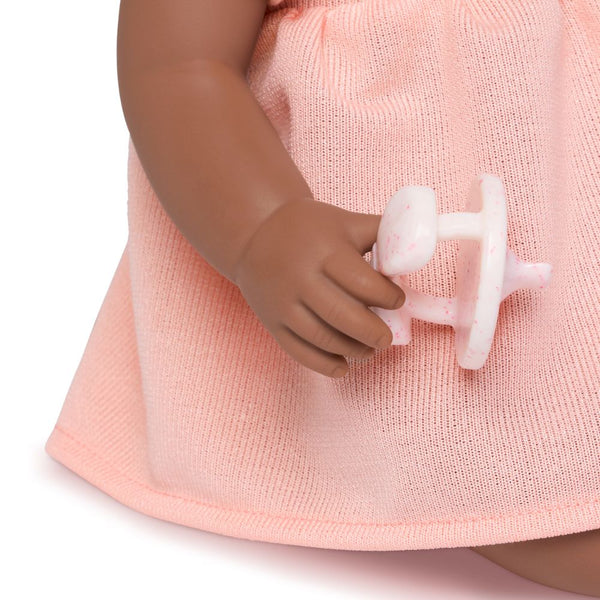 Babypuppe mit Schnuller – in einem orangefarbenen Kleid und mit einem Stirnband