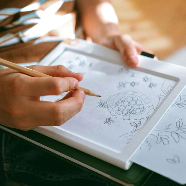 Kinderhand paust mit Bleistift ein Motiv auf dem beleuchteten Tablet ab