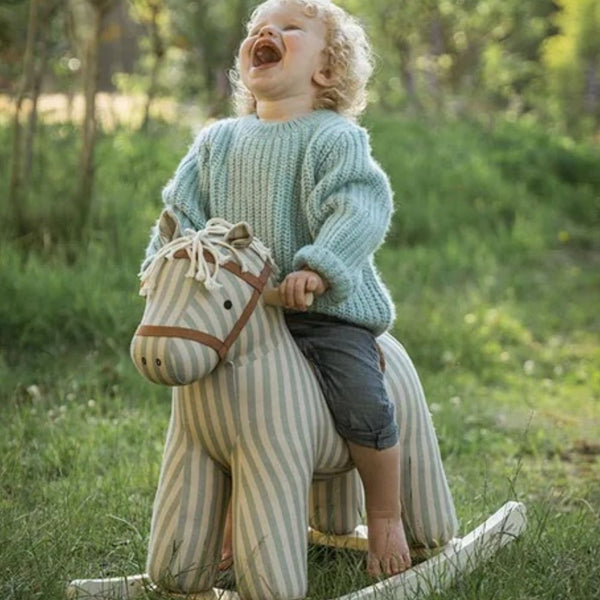 Kind reitet auf dem Schaukelpferd Sam AIDEN im Garten