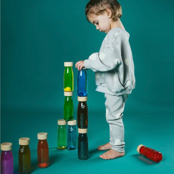 Kind spielt mit Beobachtungsflasche Fische Kinder und stapelt bunte Flaschen aus Holz