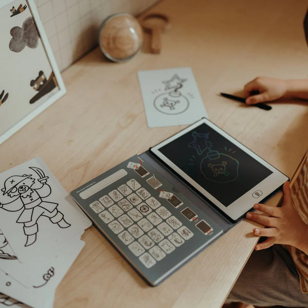Grafiktablett Kidydraw Mini Ozean & Piraten auf einem Tisch mit Kinderhand und Zeichnungen