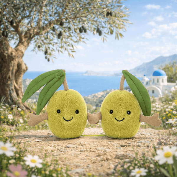 Zwei knuddelige Plüsch Oliven Jellycat mit fröhlichen Gesichtern in einer malerischen Landschaft