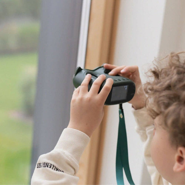 Kind verwendet das Digitalmikroskop KidLupe zur Untersuchung von Objekten durch ein Fenster