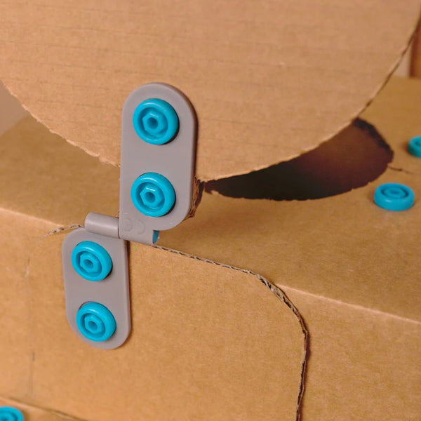 Makedo Spin-Scharnier-Set 6-tlg. mit grauen Scharnieren und blauen Befestigungen an Karton