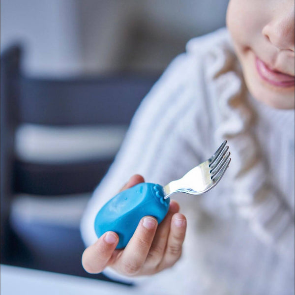 Kind hält eine Gabel mit blauem Griff von Nana's Manners Gabel und Löffel STUFE 2 – Blau