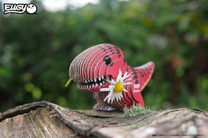 Eugy Öko 3D Puzzle Tyrannosaurus in lebendigen Farben mit einer Blume im Mund auf einem Baumstamm