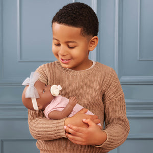 Babypuppe mit Schnuller im rosa Musselinoutfit mit Stirnband