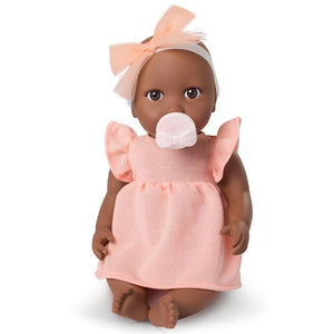 Babypuppe mit Schnuller – in einem orangefarbenen Kleid und mit einem Stirnband