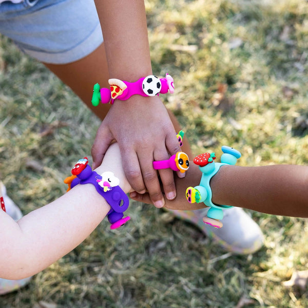 Schmuckset Plip Charms – Violett mit bunten Armbändern und Charms an Kinderhänden im Freien
