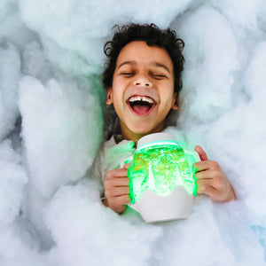 Kind hält Sensorik-Glas zum Befüllen mit Wasser – grau von Glo Pals und lacht vor Freude