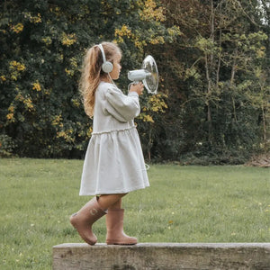 Junges Mädchen in einem weißen Kleid mit einem Soundverstärker für Kinder im Freien