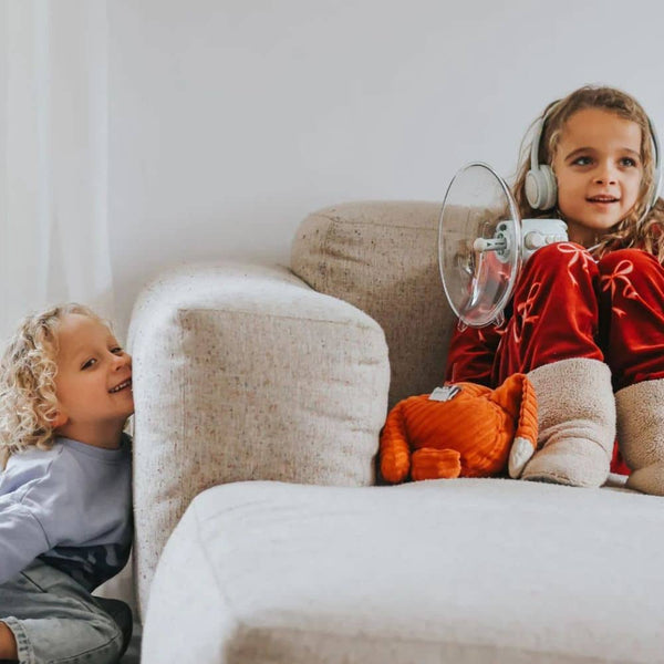 Soundverstärker für Kinder mit einem Mädchen, das Kopfhörer trägt und entspannt auf einem Sofa sitzt