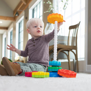Fröhliches Kind beim Spielen mit dem Fat Brain Toys SpinAgain Stapelturm kaufen auf einem Teppich
