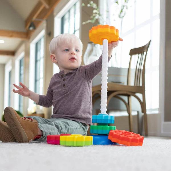 Fröhliches Kind beim Spielen mit dem Fat Brain Toys SpinAgain Stapelturm kaufen auf einem Teppich